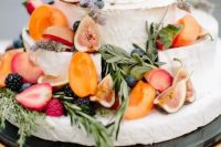 a small and cool cheese wheel wedding cake topped with fresh fruit and berries, herbs for a bright summer wedding