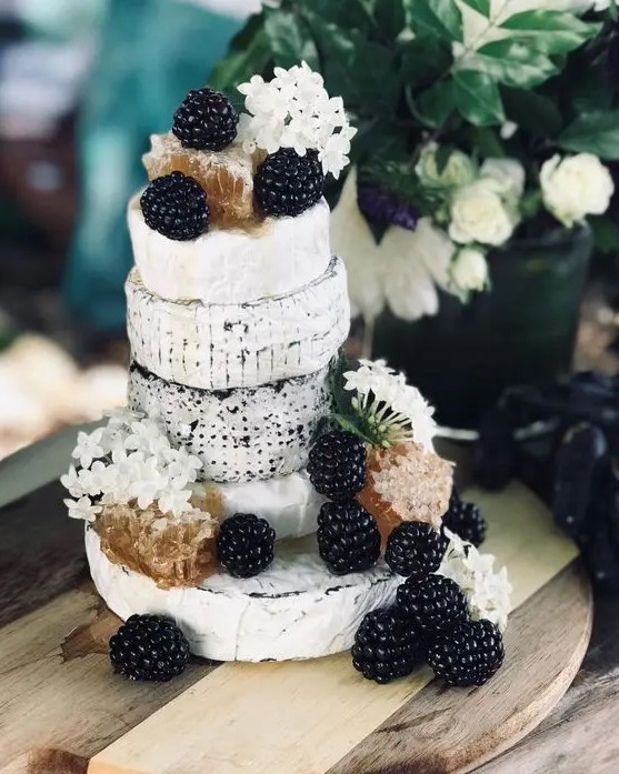 a small cheese wheel wedding cake topped with blackberries, white blooms and honey combs is a lovely idea for a summer or fall wedding