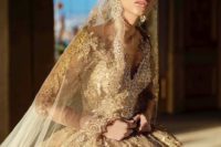 a stunning gold wedding ballgown with intricate gold lace all over the dress, with illusion sleeves, a matching veil and a crown
