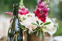 a tin vase with fuchsia and white blooms, a wine bottle as a table number and some candles for a centerpiece