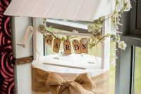 a unique wedding card box styled as a well decorated with burlap, a banner and some vines and blooms is a great idea for a vintage wedding