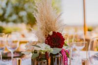 a vineyard wedding centerpiece of a gold trey, apothecary bottles, blush and burgundy blooms, greenery and pampas grass