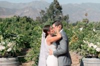 a vineyard wedding ceremony in the vines, with barrels with white florals and greenery is a cool idea not only for a fall wedding