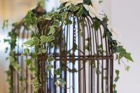 a vintage cage decorated with vines and white blooms, with a calligraphy word is a refined wedding card box idea