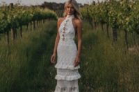 a whimsical boho sheath wedding dress with a halter neckline, layers and various types of detailing