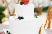 a white buttercream wedding cake with fresh apples, a pear and blackberries is a stylish idea for a fall vineyard wedding