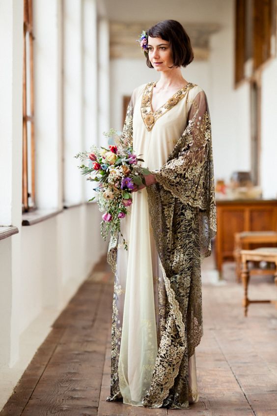 an art deco wedding dress with a neutral main dress, a gold embellished and applique neckline, super wide gold lace sleeves going dow to the floor