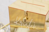 an exquisite glossy gold card box with a lock and calligraphy on it will fit most of modern and glam weddings