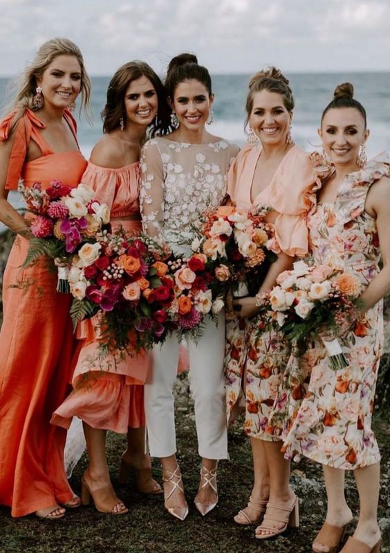 gorgeous mismatching bridesmaid dresses - solid orange ones and peachy floral ones are great for a beach wedding with a pop of color