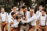 pretty groomsmen with rust pants, amber leather suspenders, brown shoes and white shirts plus black bow ties are awesome for a tropical or beach wedding
