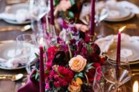 a beautiful Christmas wedding centerpiece with peachy, red, burgundy, plum-colored blooms, a purple table runner and candles