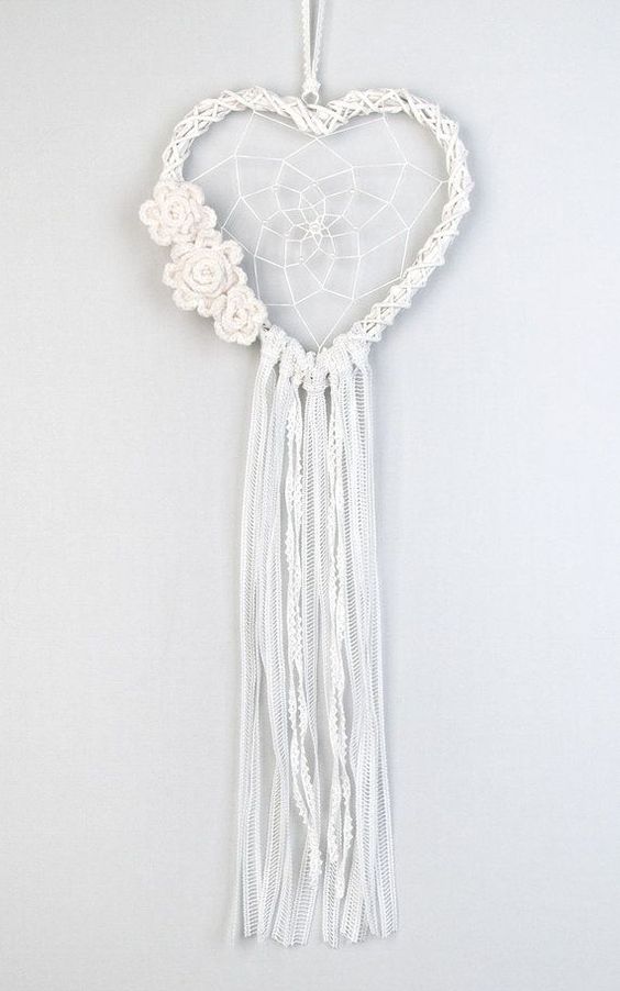 a beautiful macrame wedding dream catcher shaped as a heart, with macrame flowers and long ribbon is amazing