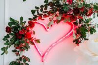 a beautiful wedding decoration of a neon heart, red roses and greenery is a lovely and bright decoration for a wedding