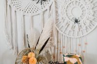 a boho Halloween bridal shower sweets table with a whimsical colorful fringe cake, glazed donuts with an edible cat and feathers