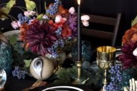 a bold Halloween bridal shower table setting with bold blooms, black candles and plates, gold glasses and cutlery is wow