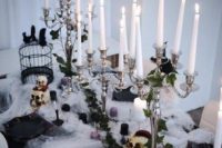 a bold Halloween bridal shower tablescape with spider web, tall and thin candles, black balls and skulls, a cage and black plates