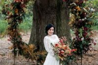 a bold fall wedding woodland wedding arch with leaves, greenery and blooms features plenty of texture and cool colors