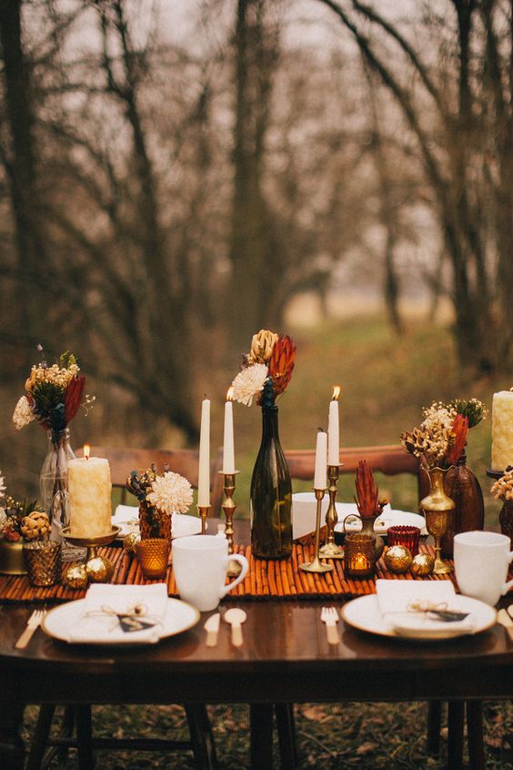 a bright Thanksgiving wedding tablescape with a bamboo runner, candles, bright blooms and gold touches is amazing