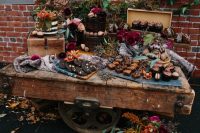 a bright fall dessert display of a large cart, bright blooms, greenery, moss and desserts and sweets
