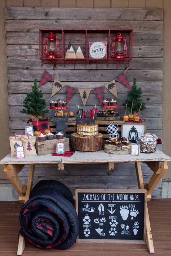 a camp dessert table with tree slices, tree stumps, wooden boxes, fir trees, plaid and lanterns is very cool