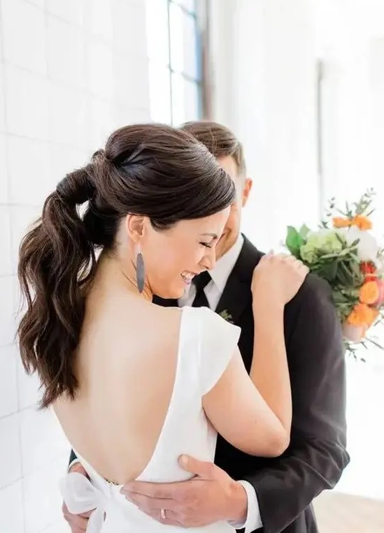 a casual ponytail with waves and twists is perfect for a modern or minimalist bride
