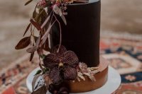 a catchy black and gold wedding cake decorated with moody blooms, dark foliage and berries is a fantastic idea for a boho wedding