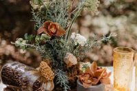 a catchy cluster fall wedding centerpiece of textural greenery, bold blooms, coffee beans on a wood slice and yellow glasses