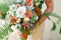 a catchy fall woodland wedding bouquet of neutral and coral blooms, seed pods, berries, greenery and mushrooms is amazing