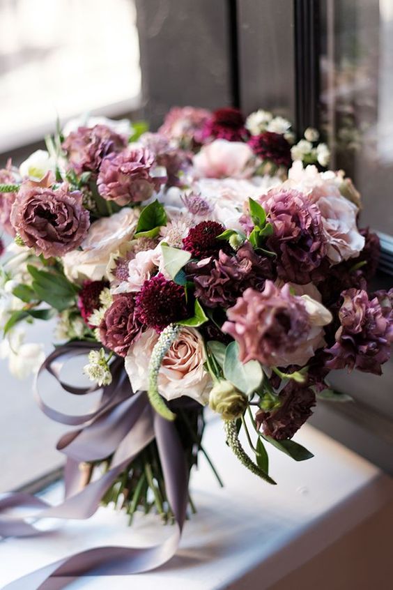 A catchyw edding bouquet with mauve, plum colored, blush and white blooms and leaves is a lovely solution for a fall bride
