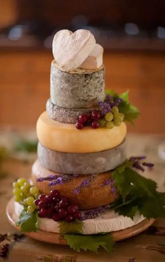 a cheese tower instead of a wedding cake, topped with grapes and lavender, cheese hearts instead of toppers