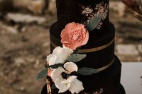 a chic and eye-catchy black wedding cake with painted flowers, sugar and fresh blooms, foliage and gold stripes for a fall wedding