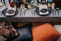 a chic table setting with a low table, black chargers and candles, moody blooms and antlers plus feathers is amazing for a Halloween bridal shower