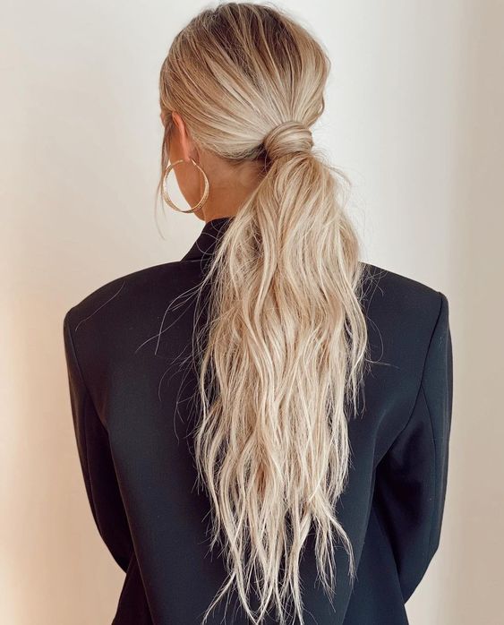 a classy messy and textural low ponytail with a messy top and hair wrapping it is a cool idea for a modern bridal look