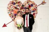 a colorful flower heart wedding backdrop is a bright and cool decor idea for a wedding, not only a Valentine’s one