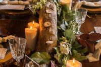 a cool fall woodland wedding reception table with a log candlelabra, candles, a clear table number and wood slice placemats