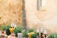 a cozy Tuscany wedding tablescape with potted herbs, spaghetti in jars, candles, fresh tomatoes and peppers and woven placemats