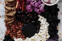 a dark Halloween inspired cheese bord with nuts, berries, veggies and dried fruit is a gorgeous idea for a vegetarian Halloween bridal shower