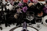 a decadent Halloween bridal shower tablescape with black, lilac, pink blooms and dark foliage, black chargers and purple napkins is amazing