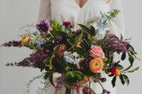 a dimensional and textural wedding bouquet with plum-colored, blue and orange blooms, leaves and ferns is wow
