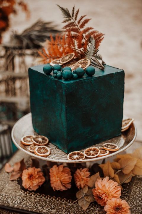 a dramatic square black wedding cake with dried citrus, berries and dried herbs on top for a refined boho wedding is a wow idea