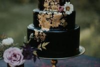 a dreamy dark romance black wedding cake with gold leaf, some neutrals and pastel blooms and twigs is a beautiful idea for a fall or Halloween wedding