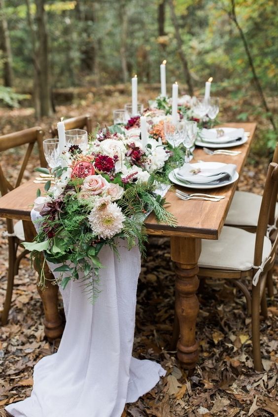 a fall woodland reception table with greenery, fuchsia, blush blooms, fruits and candles is a classy and chic idea