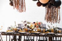 a gorgeous Halloween bridal shower reception with a dark balloon installation, florals, mustard napkins and black candle lanterns