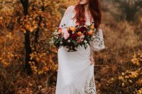 a gorgeous fall woodland wedding centerpiece of pink, yellow and burgundy blooms and greenery is a lush and bold idea