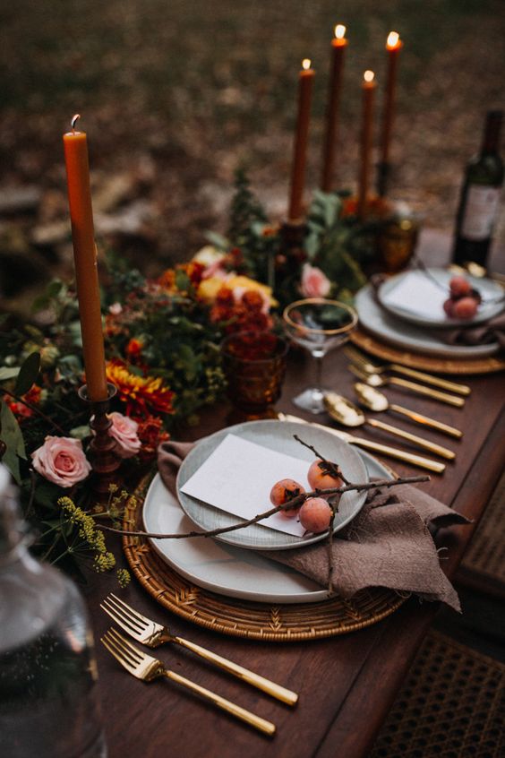 a gorgeous fall woodland wedding tablescape with bold blooms, berries, greenery, rust-colored candles, woven placemats, gold touches is amazing