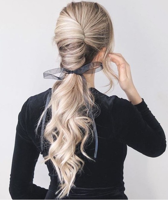 a gorgeous low chignon going into a long wavy pinytail and a sheer and etherel grey ribbon with a bow