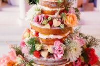 a gorgeous naked wedding cake decorated with hearts, strawberries, pink and white blooms and greenery is amazing for summer