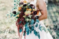 a gorgeous wedding bouquet with greenery and cascading blooms, purple and rust flowers