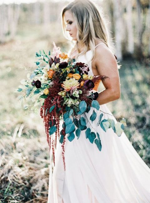 a gorgeous wedding bouquet with greenery and cascading blooms, purple and rust flowers