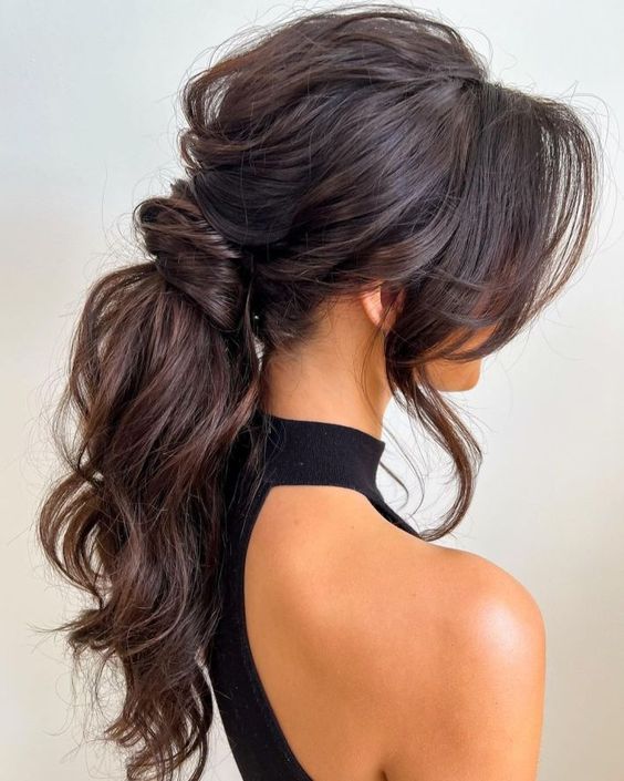a jaw-dropping wavy messy low ponytail with a messy volume on top, locks framing the face is amazing for a glam bride